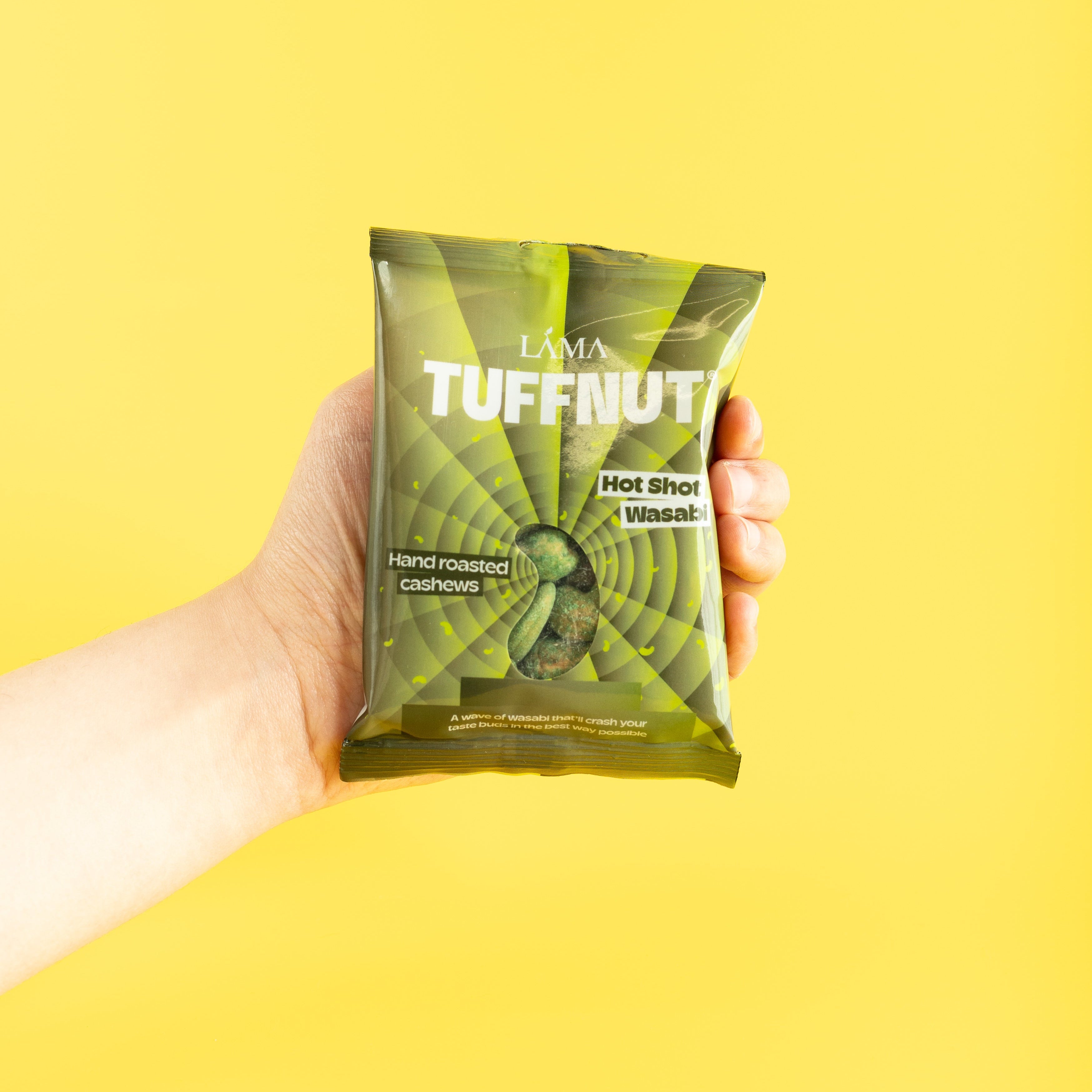 Hand holding a green package labeled 'Tuffnut' against a yellow background